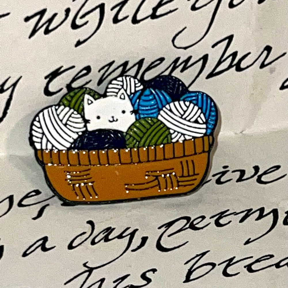 Cat in yarn basket enamel pin